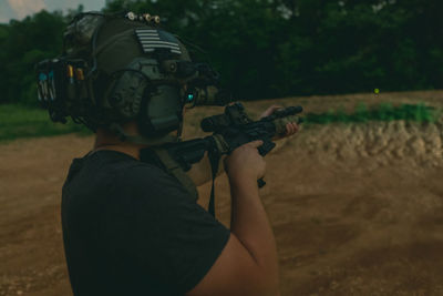 Rear view of man holding umbrella on land