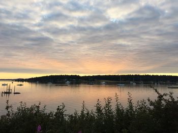 Scenic view of lake against cloudy sky at sunset