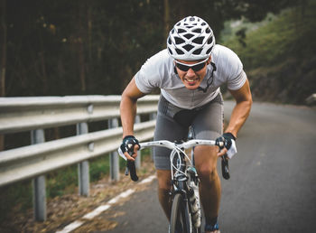 Full length of man riding bicycle on road by railing