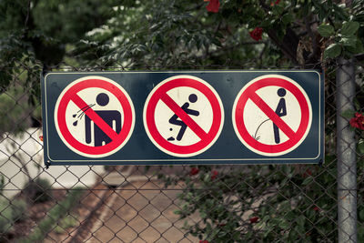 Close-up of road sign on fence