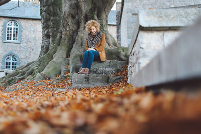 Young woman sitting by tree