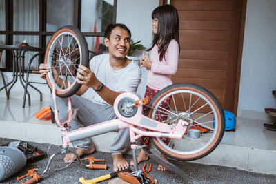 Father repairing bicycle with daughter at home