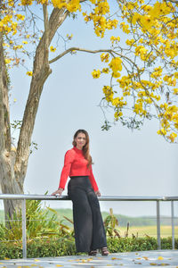 Portrait of young woman standing against trees