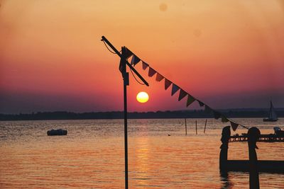 Silhouette people by sea against sky during sunset