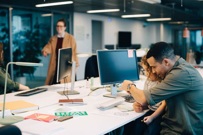 Businessman with son sitting at desk in creative office