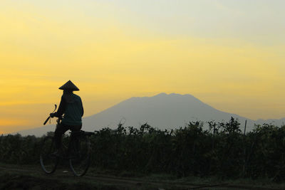 Man cycling against sky during sunset