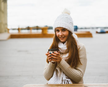 Young woman drinking coffee while sitting at outdoor cafe