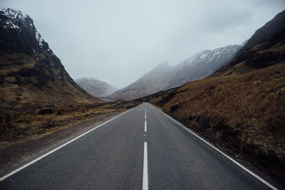 Road leading towards mountains against sky