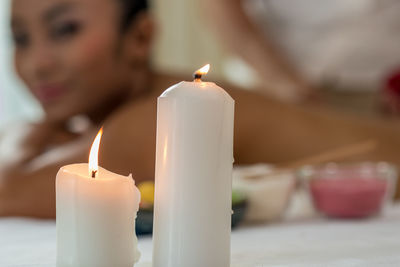 Close-up of candles with woman relaxing in background at spa