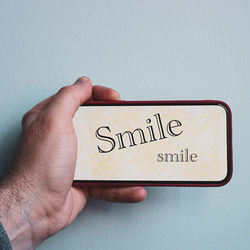 Cropped hand of person holding text against wall