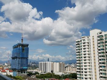 Buildings in city against cloudy sky