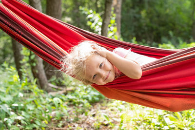 Portrait of a smiling young woman looking away while lying in hammock