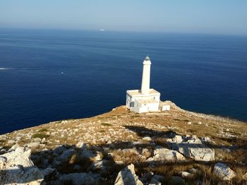 Lighthouse by sea against sky