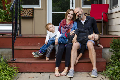 A happy family sit close together in their front yard