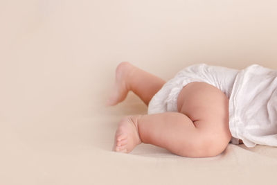 Low section of baby lying on bed