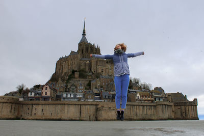 Woman in jump against the mont saint michel in france