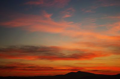 Scenic view of silhouette mountains against orange sky