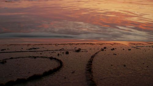 Surface level of beach against sky during sunset