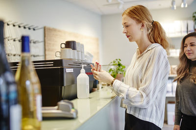 Woman in cafe applying hand sanitizer