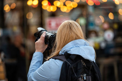 Blonde middle-aged woman with a photo camera in the evening on the city streets, lifestyle concept