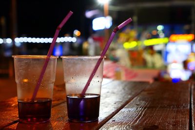 Close-up of drinks on table at sidewalk cafe at night