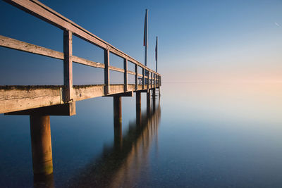 Pier over sea against clear sky during sunset