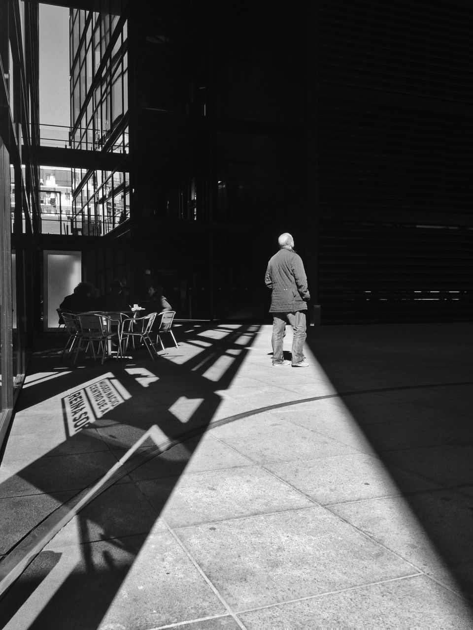 full length, rear view, walking, architecture, built structure, lifestyles, building exterior, men, city, leisure activity, tiled floor, shadow, casual clothing, the way forward, sunlight, sidewalk, person, footpath