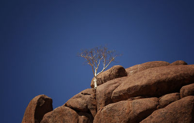 Low angle view of rocks against clear blue sky