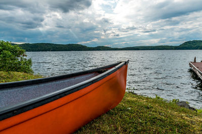 Bright red canoe on the shore line, with dramatic sunlight in the evening cloudy sky.