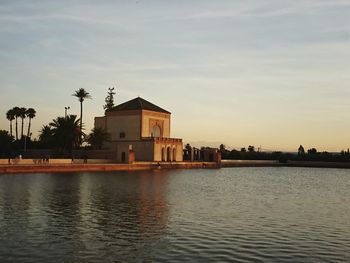 Buildings by swimming pool against sky during sunset