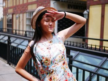 Portrait of young woman standing against railing