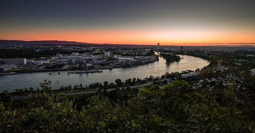 High angle view of sea and cityscape against sky during sunset