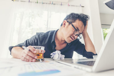 Midsection of man using mobile phone while sitting on table