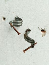 Rusty nails with brackets on white wall