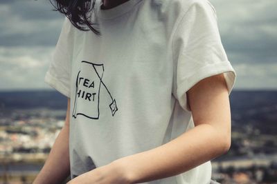 Midsection of woman holding text against sky