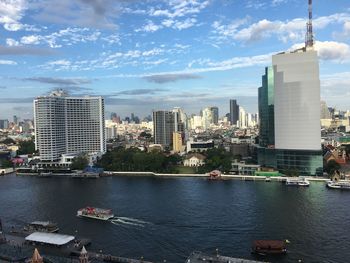 View of buildings at waterfront against cloudy sky