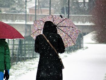 Rear view of person walking on road during snowfall