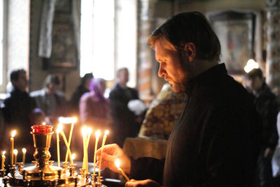 Side view of man igniting candles in church