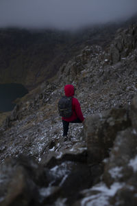 Rear view of man standing on rock at mountain