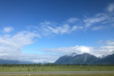 Scenic view of field and mountains against blue sky