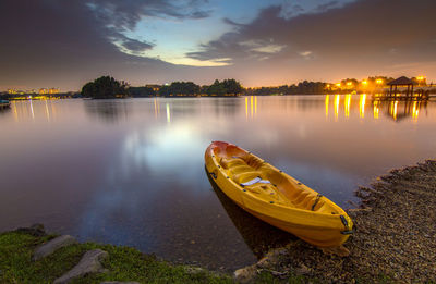 Canoe moored at lake during sunset
