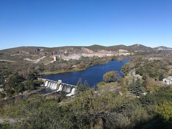 Scenic view of lake and mountains against clear blue sky