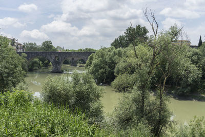 Arch bridge over river against sky