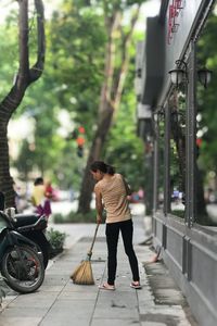 Woman sweeping on sidewalk