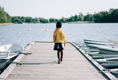 Young girl walking along a pier towards the sea in sweden