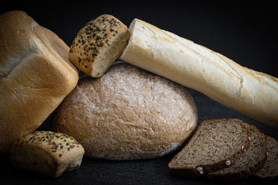 Two breads, half a french baguette and buns on the table.