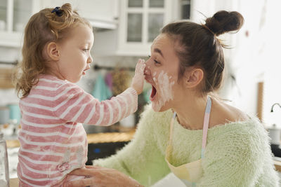 Mother and daughter preparing food in kitchen at home