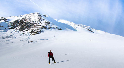Low angle view of man standing on snowcapped mountain