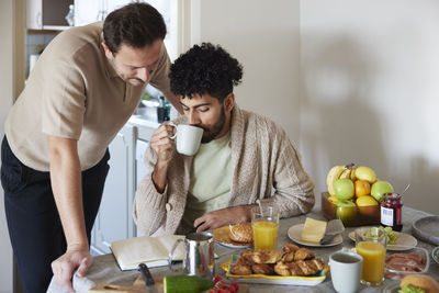 Happy gay couple eating breakfast at home