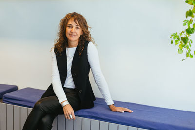Portrait of young woman standing against wall